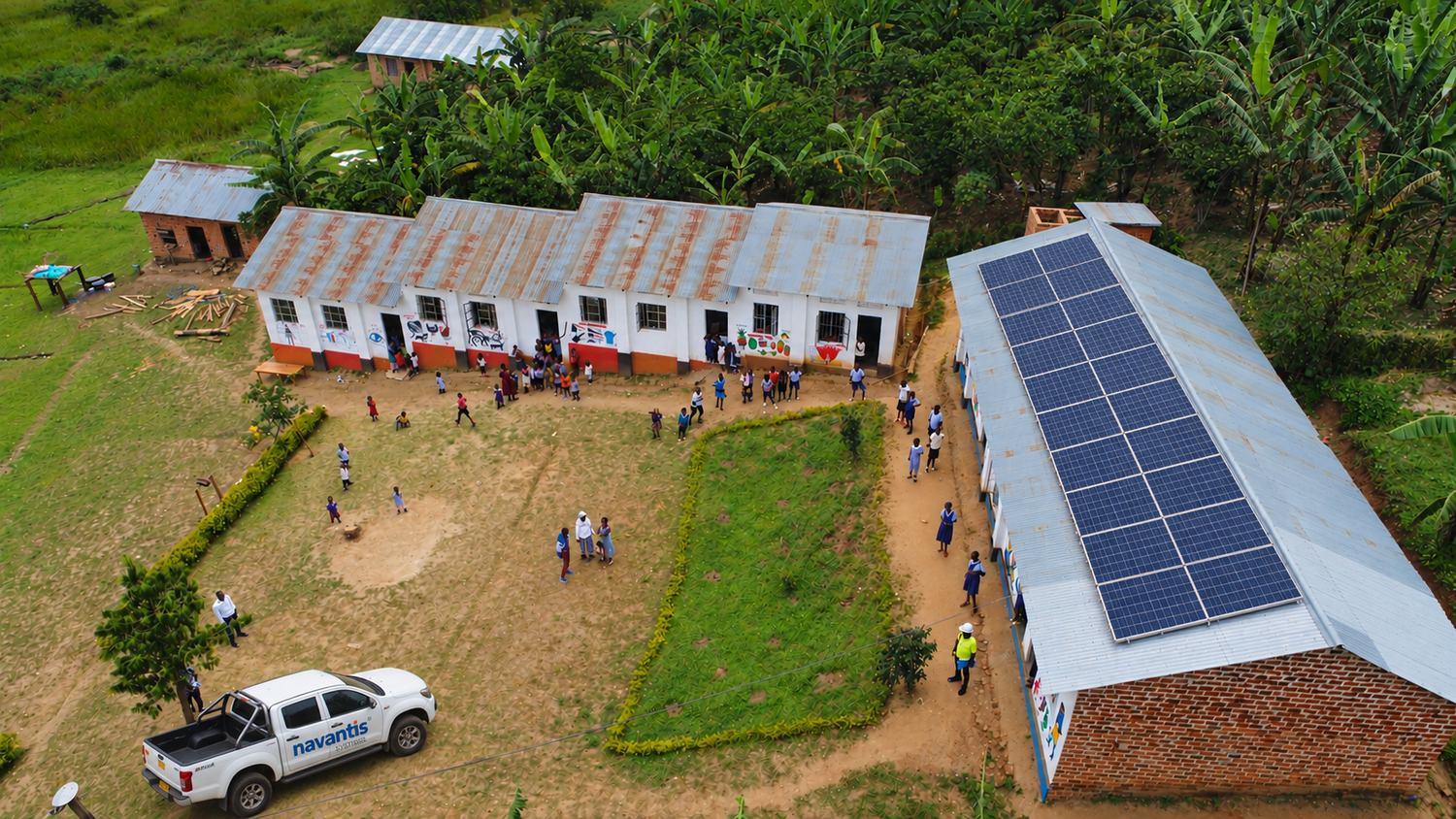 Aerial view of a rural primary school with a large rooftop solar array and a Navantis service vehicle